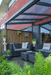 Outdoor patio with gray sectional sofa, plants, and a wooden wall.