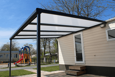 Covered outdoor area in front of a building with playground equipment in the background.