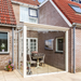 Glass extension attached to a brick house with a patio area and table.