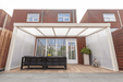 Outdoor patio with pergola, table, and chairs in front of a brick building.