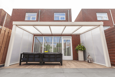 Outdoor patio with pergola, table, and chairs in front of a brick building.