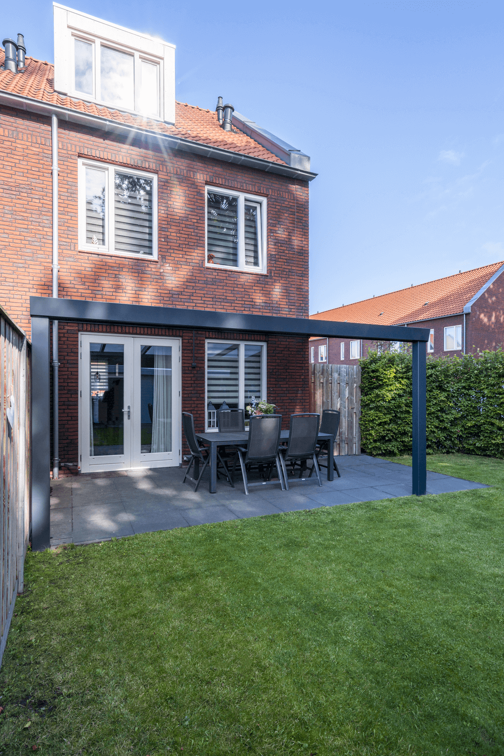 Outdoor patio area with a Veranda attached to a brick house.