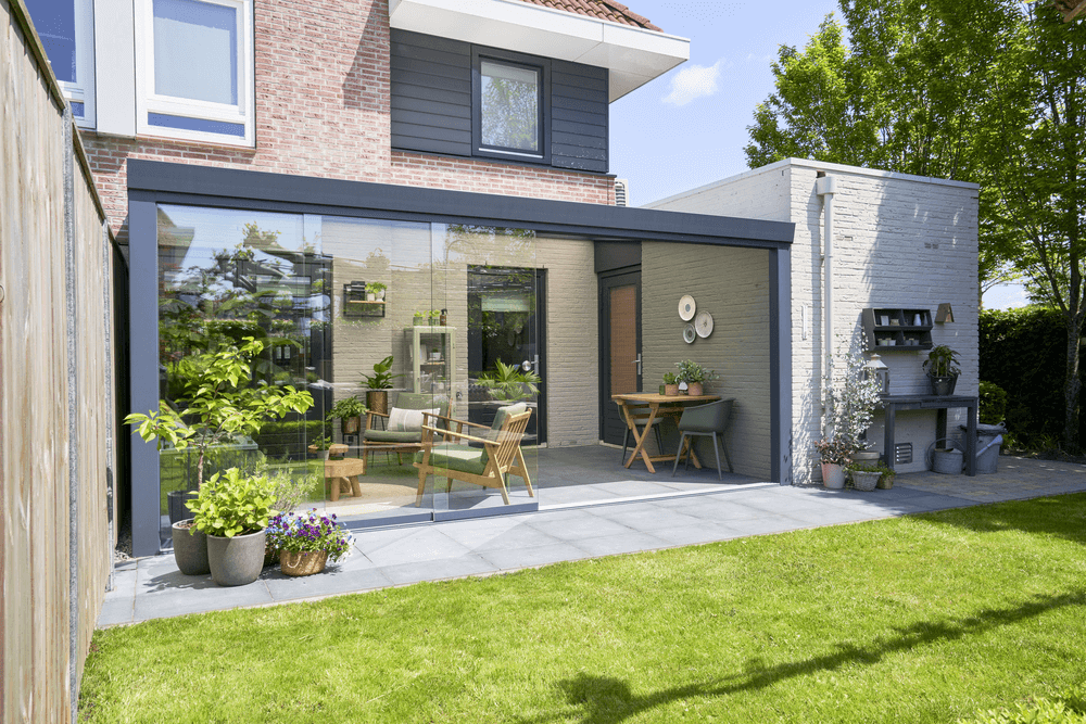 Modern house exterior with a patio area, garden, and outdoor furniture.