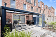 Modern outdoor patio area with furniture and a glass door leading indoors.