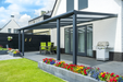 Outdoor patio with pergola, chairs, and a grill in a residential setting.