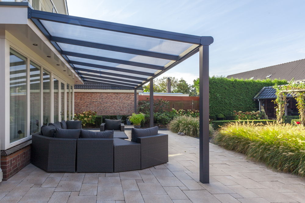 Outdoor patio area with a pergola and seating furniture on a sunny day.