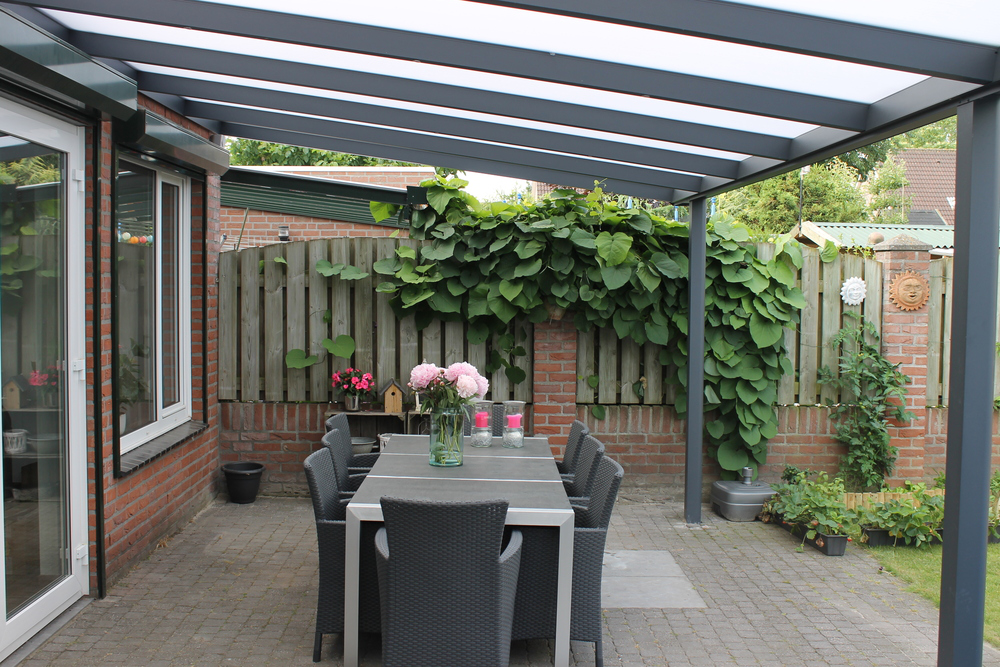 Outdoor patio with pergola, table, chairs, and plants
