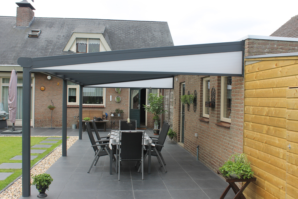 Patio area with pergola, outdoor furniture, and plants in a residential setting.