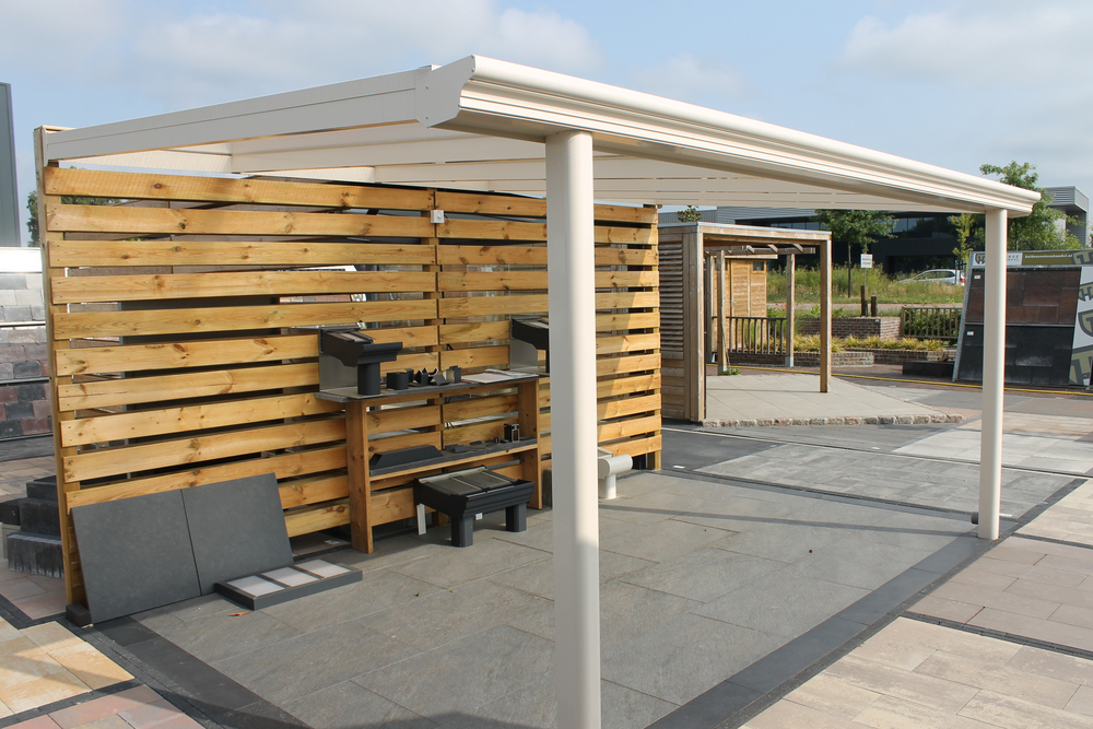 Outdoor patio with wooden privacy screen, table, and chairs under a white pergola.