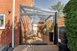 Garden room extension with glass door and deck area, featuring a brick wall and outdoor furniture.