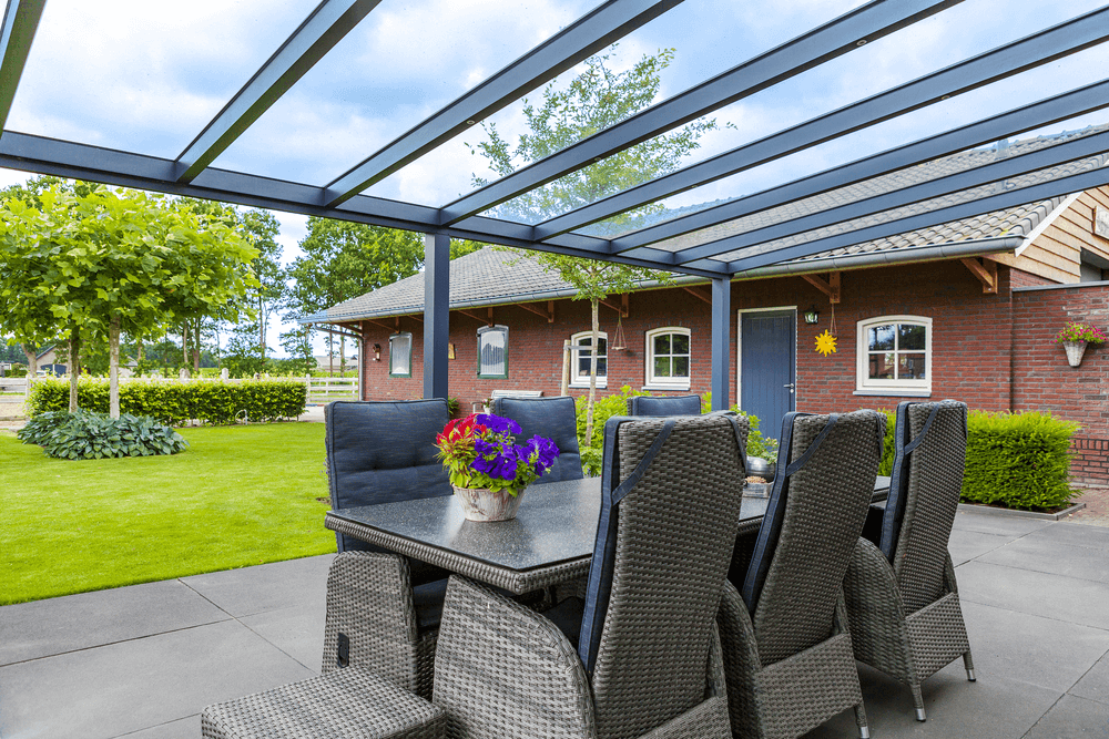 Outdoor patio area with furniture and a table under a glass roof.