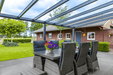 Outdoor patio area with furniture and a table under a glass roof.