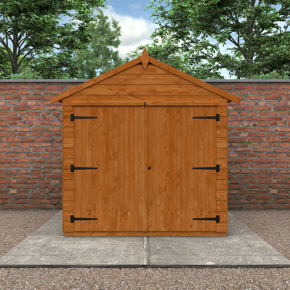 Wooden shed with a triangular roof against a brick wall and trees.