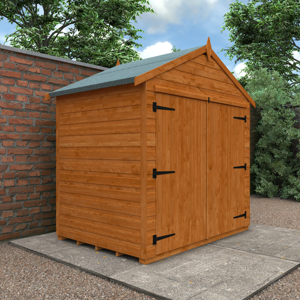 Wooden shed with a green roof on a concrete patio next to a brick wall and trees.