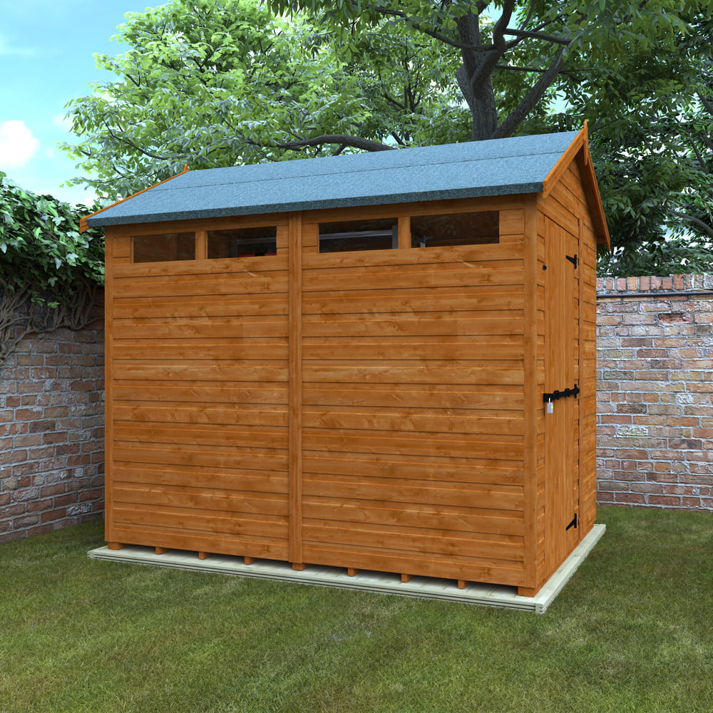 Wooden shed with a gray roof in a garden setting with trees and a brick wall.