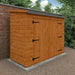 Wooden shed attached to a brick wall with greenery in the background
