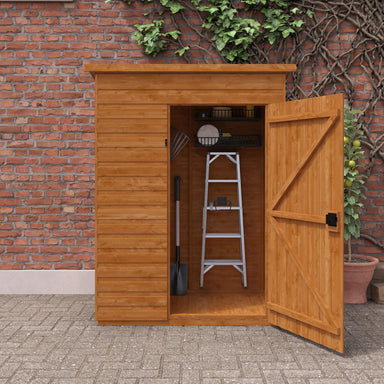 Wooden storage shed with open door showing tools against a brick wall.