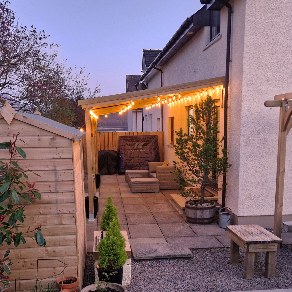 Backyard patio with string lights, outdoor furniture, and plants.
