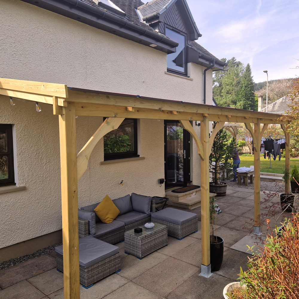Outdoor patio area with a wooden gazebo, sofa set, and potted plants in a garden setting.