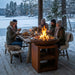 Friends eating by a HEAT Bakka plancha grill beside a snowy lake