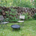 HEAT Classic black fire bowl on legs on a garden lawn with two folding chairs