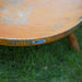 Close-up of a HEAT Classic rust fire bowl rim and wooden-look leg on grass