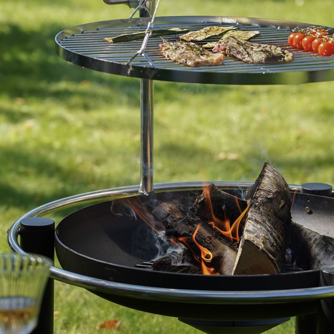Meat and vegetables on the HEAT Pendal grill over a log fire