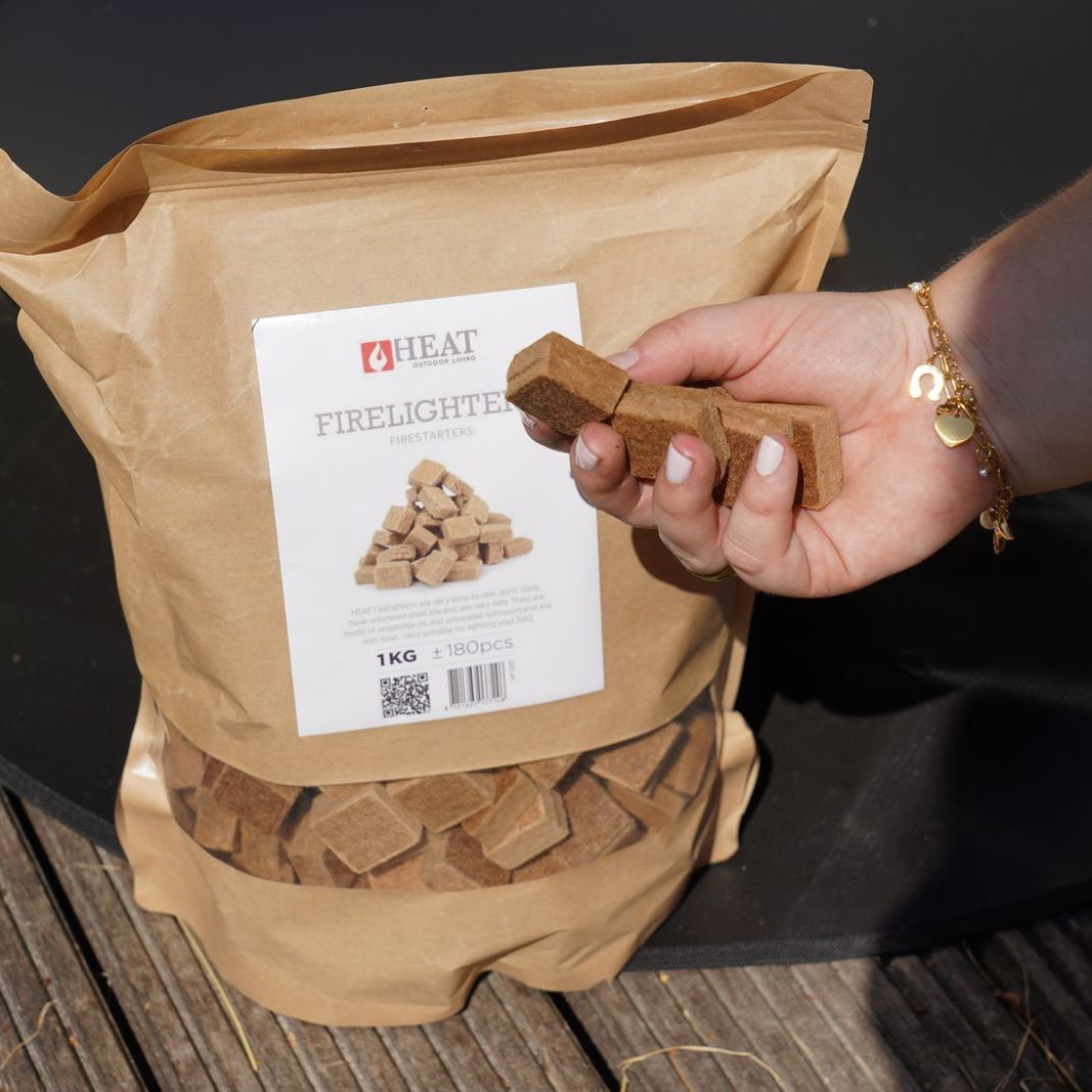 Hand taking a firelighter cube from a HEAT 1kg bag