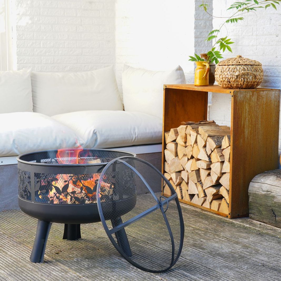 HEAT Alna fire pit burning on a patio beside a sofa and log store