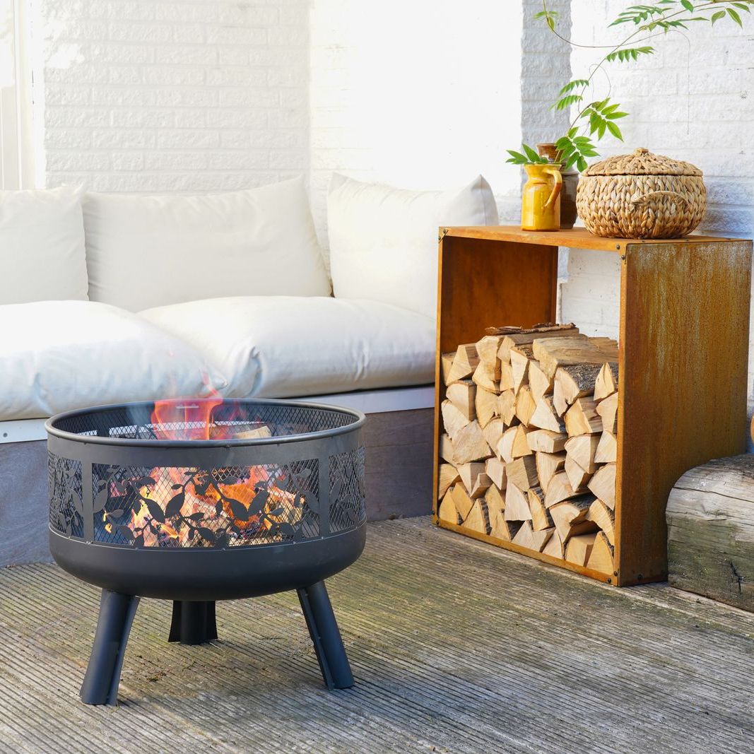 HEAT Alna fire pit with a fire on a patio next to stacked logs