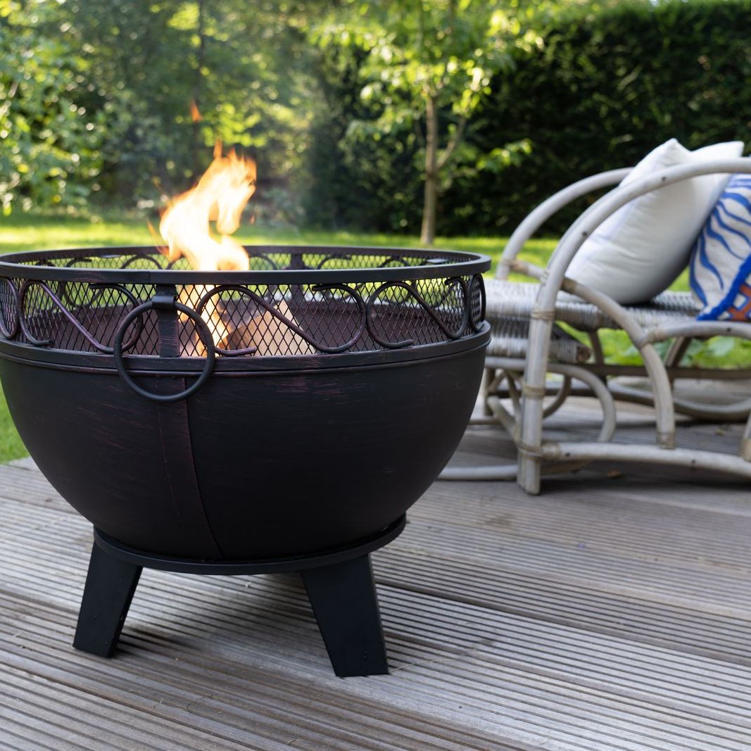 HEAT Boble fire bowl burning on decking beside rattan chairs
