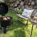 HEAT Braten charcoal BBQ with lid open and food on the grill on a lawn