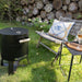 HEAT Braten compact charcoal BBQ with lid closed beside a garden chair