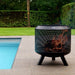 HEAT Fire Drum with a log fire on a patio by a swimming pool