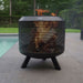 HEAT Fire Drum with logs burning on a paved patio