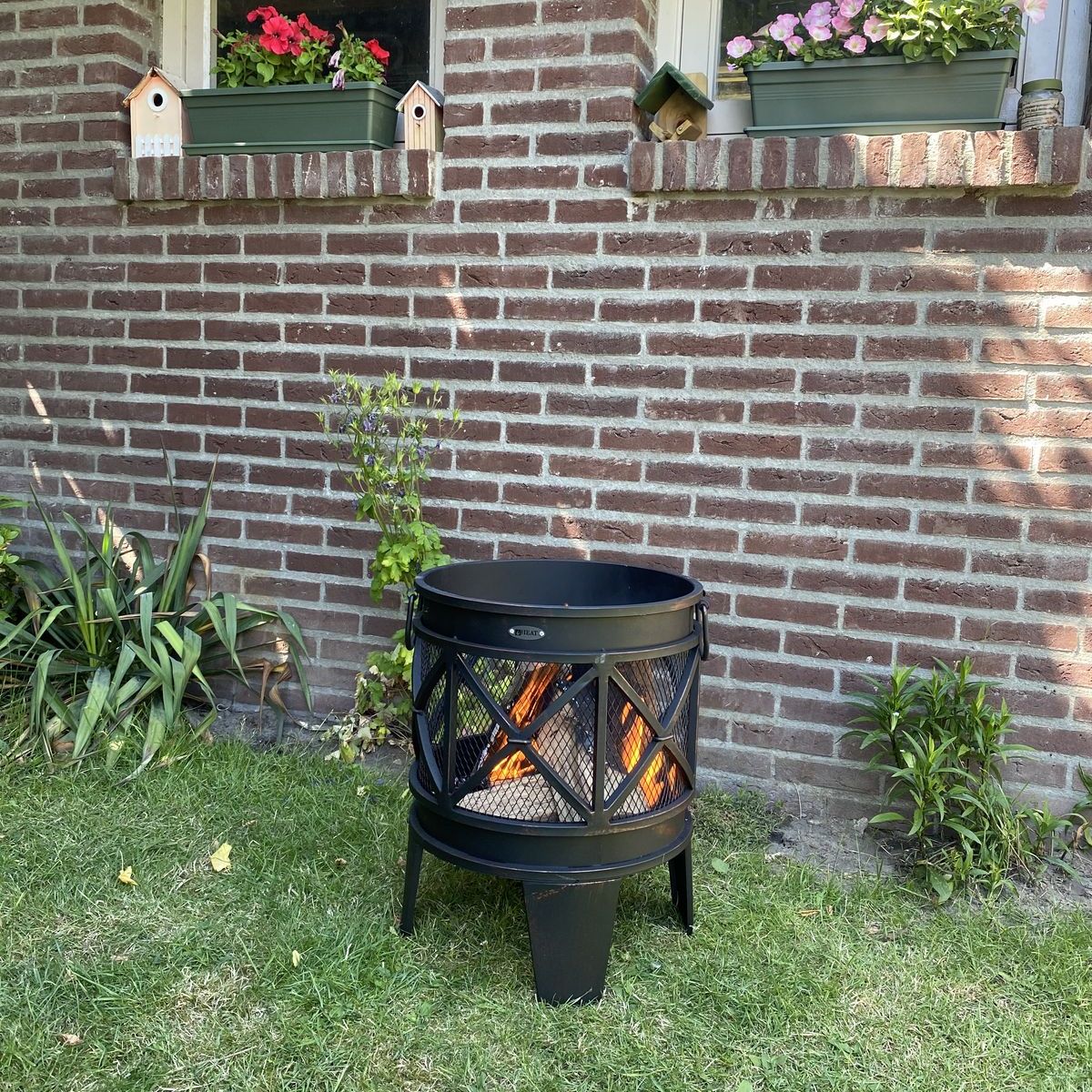 HEAT FireCask fire barrel on the lawn by a brick garden wall