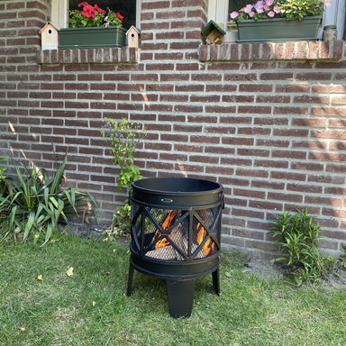 HEAT FireCask fire barrel on the lawn by a brick garden wall