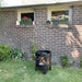 HEAT FireCask with a fire glowing, on a lawn by a brick wall