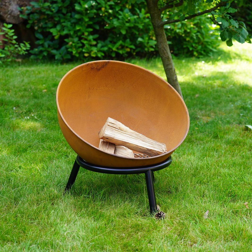 HEAT Kappa rust fire pit with logs on a garden lawn