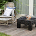 HEAT Kvadrat fire bowl with a small fire on decking beside a rattan chair