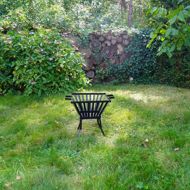HEAT Skal fire pit on the lawn of a garden with stacked logs behind