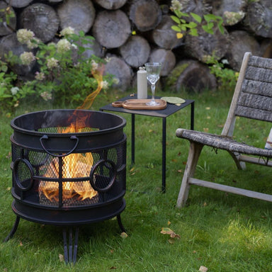 HEAT Tynset fire basket burning on a lawn beside a garden chair and side table