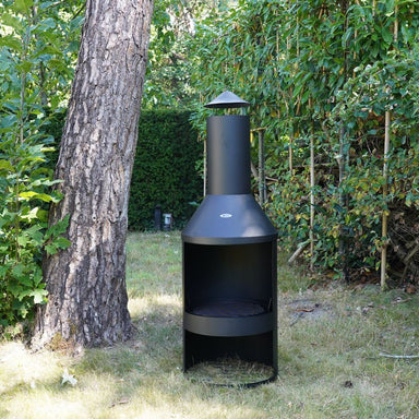 HEAT Larvik outdoor fireplace beside a tree in a garden