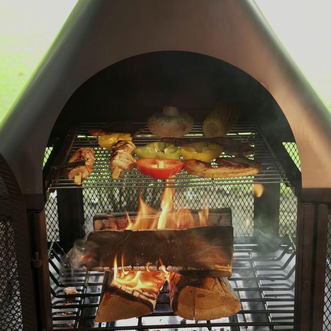 Food cooking on the grill grid inside a HEAT Saga chiminea over a log fire