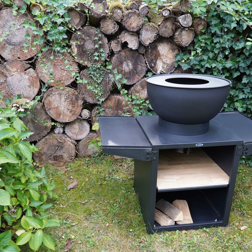 HEAT Kjok black outdoor kitchen with fire bowl and side benches, angled view