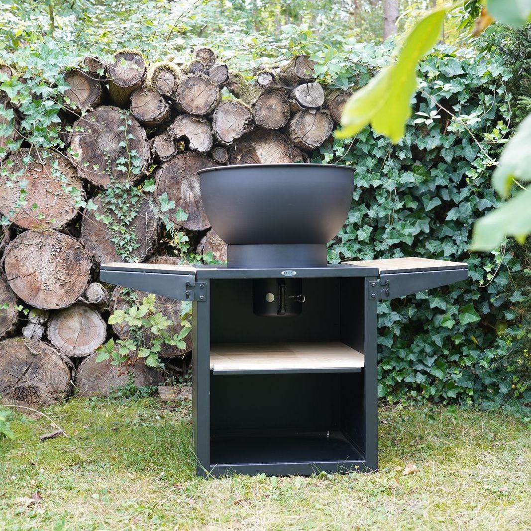 HEAT Kjok black outdoor kitchen with folded benches against a log wall