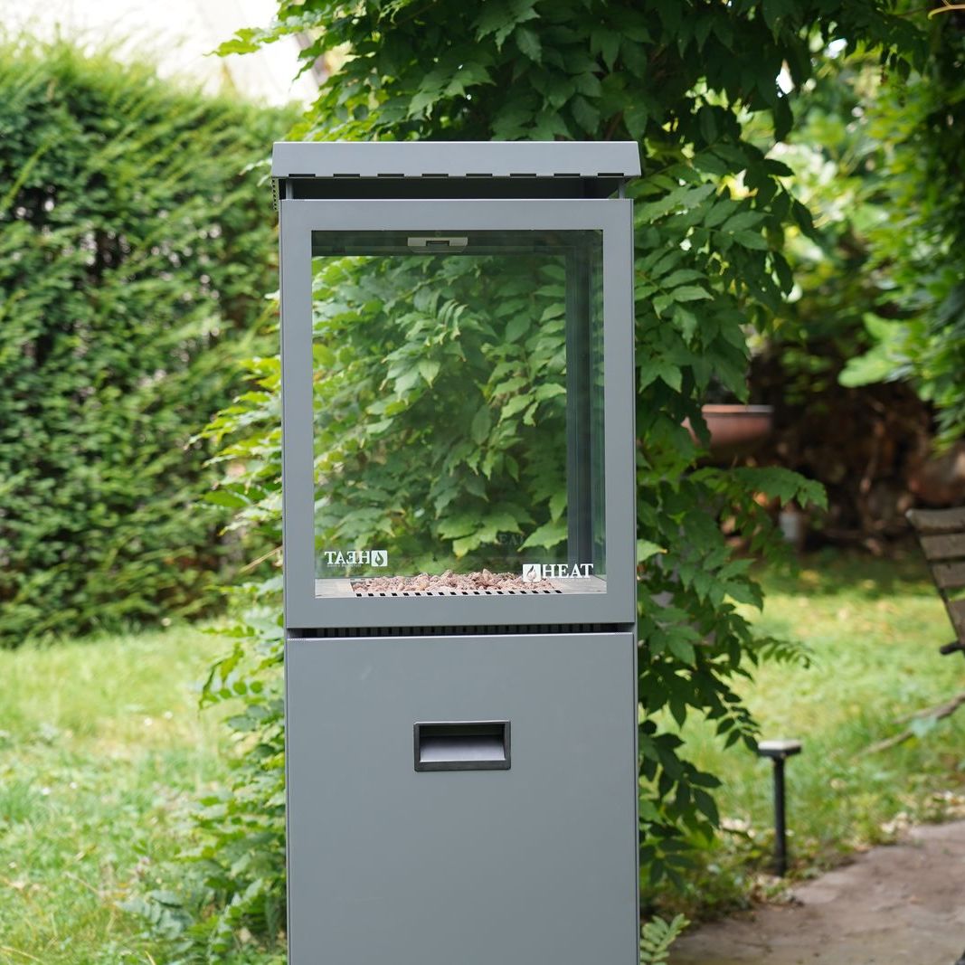HEAT Utevarme patio heater with flame lit in a green garden