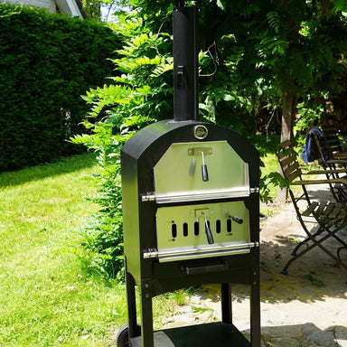 HEAT Ovnhus pizza oven standing on a garden patio by a hedge