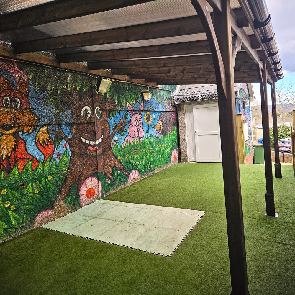 Children's mural with a tree, flowers, and animals under a gazebo