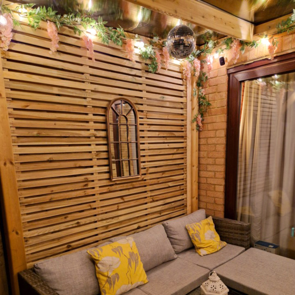 Wooden interior with a couch, yellow pillows, and decorative lights.